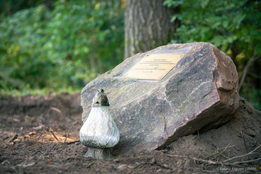 widok na pomnik z tablica pamiątkową umiejscowiony w środku lasu
