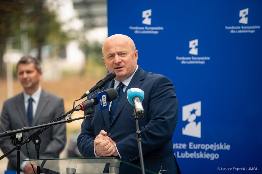 Marszałek Jarosław Stawiarski stoi przy mikrofonie ustawionym na świeżym powietrzu i wypowiada sie, za nim znajduje się ścianka RPO