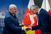 Marszałek Jarosław Stawiarski podaje rękę jednemu z beneficjentów programu, który z rąk marszałka odbiera podpisaną umowę o dotację