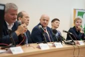 Marszałek Jarosław Stawiarski siedzi przy stole wspólnie z kilkoma innymi uczestnikami konferencji