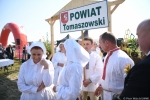 Grupa ludzi w białych strojach ludowych. jedna osoba trzyma tabliczkę nad głowami z napisem powiat tomaszowski.