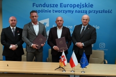 Marszałek Jarosław Stawiarski i wicemarszałek Piotr Breś pozują wspólnie do zdjęcia  z beneficjentami programu funduszy unijnych