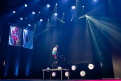 Młody chłopak na rowerze podczas pokazu akrobatycznego, który wykonuje na scenie w sali operowej