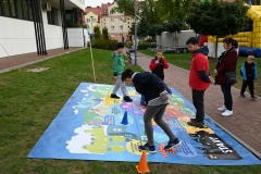 Kolorowa plansza ułożona na trawie, bawią się na niej dzieci