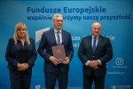 Marszałek WL oraz dwoje przedstawicieli Gminy Poniatowa pozują wspólnie do zdjęcia w sali konferencyjnej.