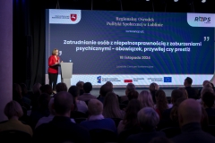 Dyrektor Małgorzata Romanko stoi przy mównicy i zwraca się do zebranych, na pierwszym planie widać siedząca publiczność