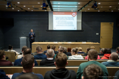 Sala konferencyjna zapełniona uczestnikami, na czele sali stoi prelegent