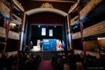 Widok na wnętrze sali teatralnej z uchwyconą widownią i balkonami po obu stronach sceny. Na scenie stoi marszałek województwa lubelskiego, który przemawia do zebranych