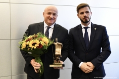 Marszałek Jarosław Stawiarski trzyma w rękach kwiaty i otrzymaną statuetkę obok niego stoi dyrektor szpitala w Białej Podlaskiej Artur Kozioł